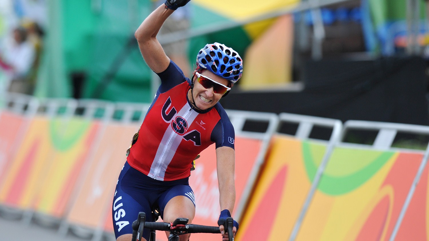 Jaime Whitmore riding on bike with hand raised in celebratory pose