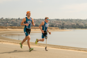 Jason and young athlete at Paratri Camp running along the water