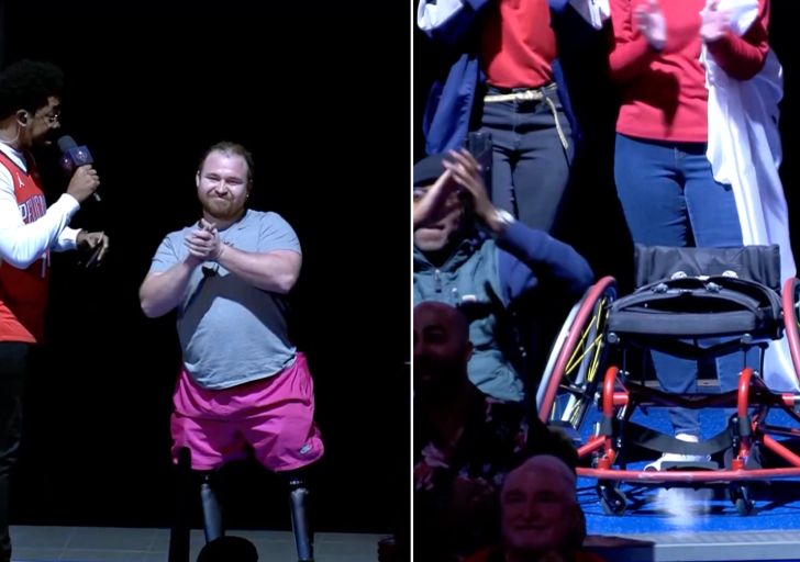 An athlete with a physical disability stands on stage clapping while a host speaks into a microphone, as supporters applaud during a live event celebration.