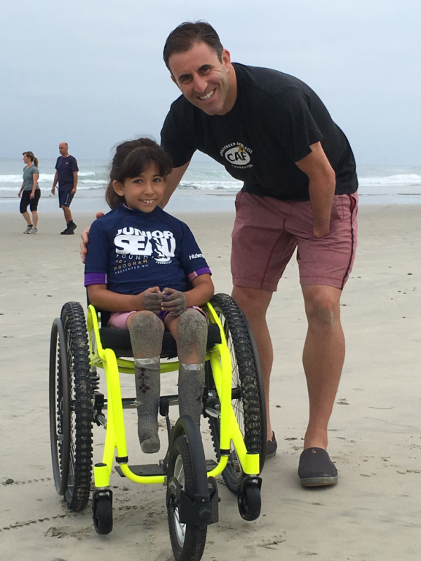 Danny Gabriel with young girl in wheelchair at beach