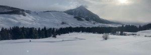 People cross country skiing next to a snowy mountain