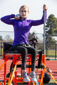 girl sitting on throwing platform with shotput in hand