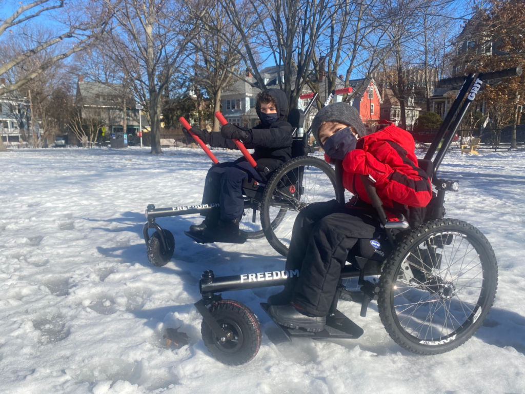 Bennie Chisolm sitting in GRIT Chair with friend in snow