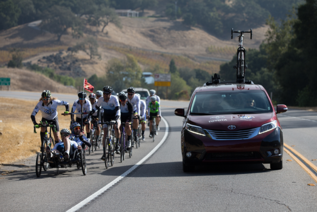 cyclists biking alongside Toyota vehicle