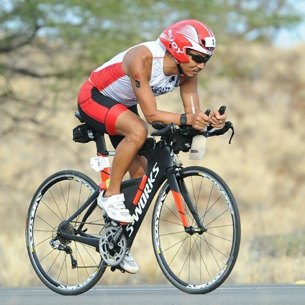 An athlete with a physical disability rides a road bike during the cycling portion of an IRONMAN race.