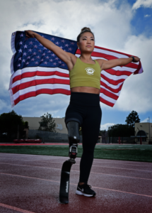Scout Bassett standing with American flag held behind her on a track