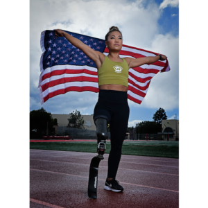 Scout Bassett standing holding American flag behind her on track