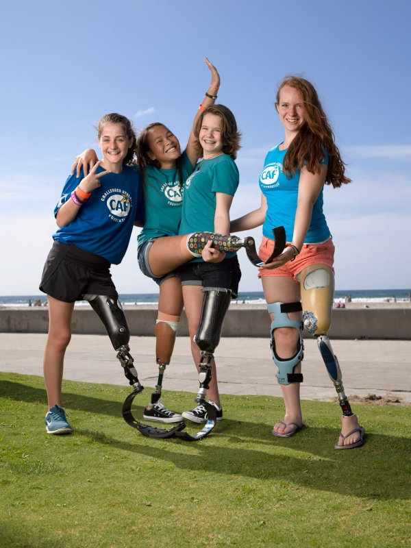 Teenagers with prosthetic legs posing for camera by the beach