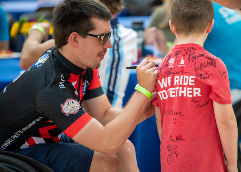 CAF cyclist signing red shirt of young fan