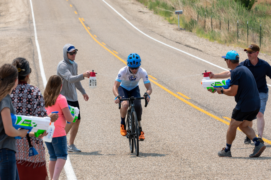 Volunteers spray water on upright cyclist participating in road race