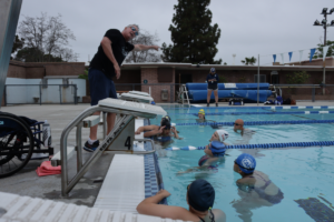 Kids in olympic swimming pool learning how to swim from instructor