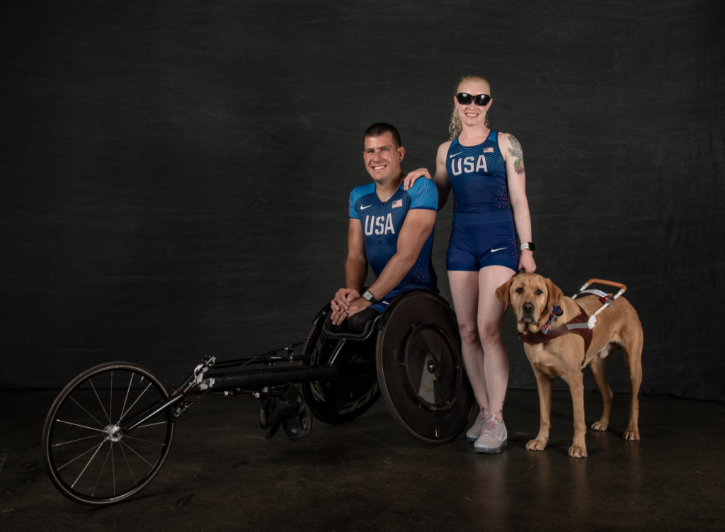 Erik Hightower and Kym Crosby Hightower in Team USA uniform against black backdrop with dog Tron