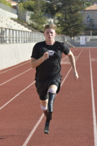 Hunter Woodhall running on track in CAF shirt