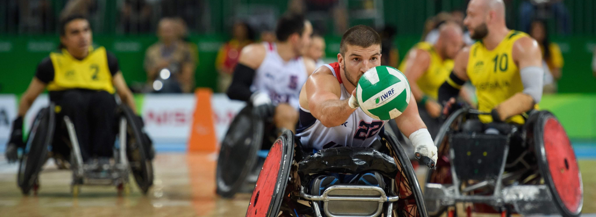 Kory Puderbaugh playing Wheelchair Rugby with rugby ball in hand