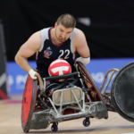 Kory Puderbaugh holding rugby ball playing Wheelchair Rugby