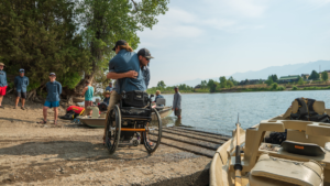 One person helping another out of wheelchair at CAF Fly Fishing and Water Adventure Camp Montana