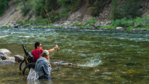 Boy in GRIT Freedom Chair Fly Fishing at CAF Fly Fishing and Water Adventure Camp Montana