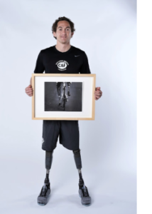 Rudy Garcia-Tolson holding framed photo of him riding a bike with two prosthetic legs