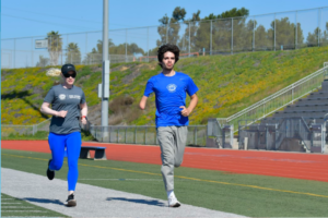 Kym Crosby Hightower running along side young athlete on track