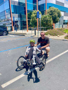 Michelle Pinard sitting in handcycle with husband outside of CAF Headquarters