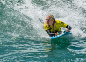 Parker Olenick laying on surfboard surfing a wave