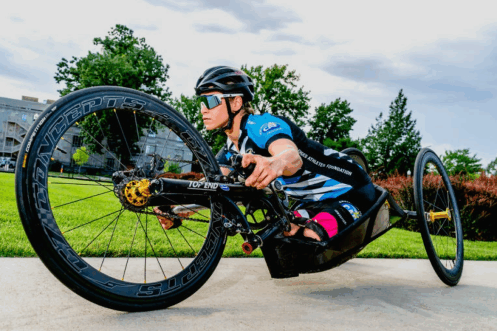 A handcyclist races outdoors, leaning low over the frame with focus and determination.