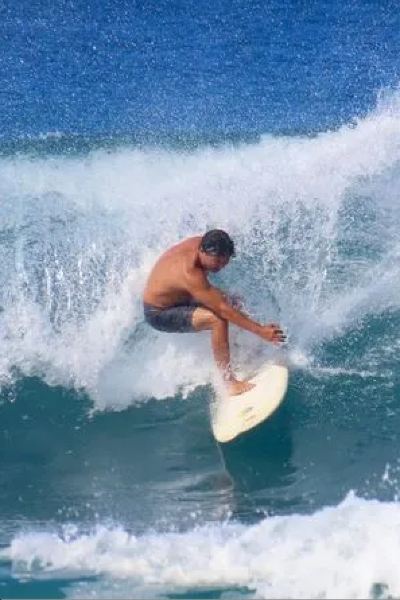 Man on surf board surfing a large wave in the ocean with a prosthetic leg 