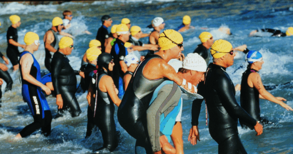 Photo of athletes starting a triathlon in the water with athlete with physical disability on the back of an able bodied athlete