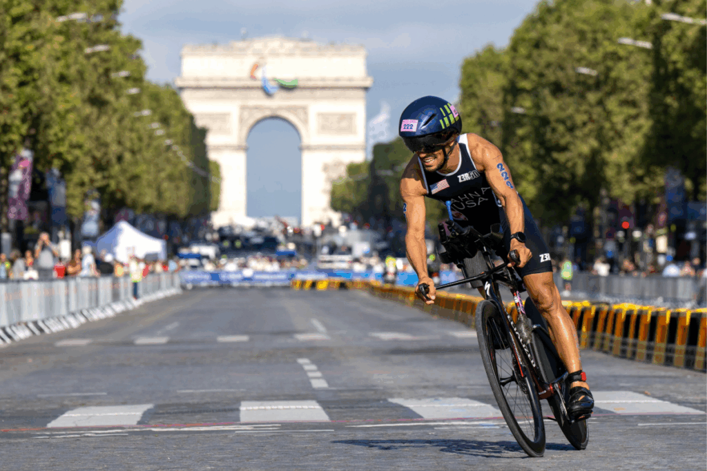 Paratriathlete Mohamed Lahna rides past the Arc de Triomphe during the 2024 Paralympic Games cycling leg in Paris.