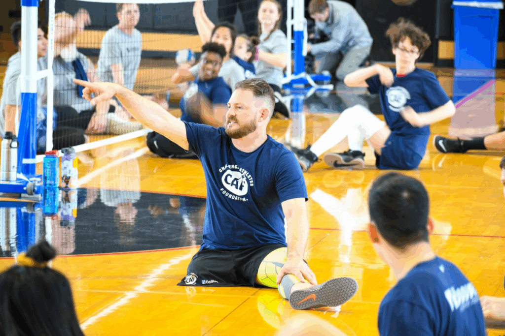 CAF Athlete ambassador josh Sweeney on a volleyball court instructing sitting volleyball