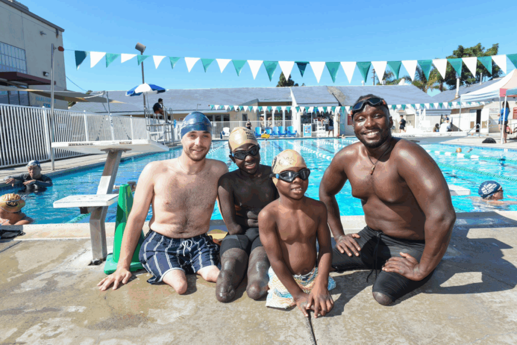 CAF athlete ambassador roderick sewell sitting outside of a pool with three other youth athletes before a swim clinic