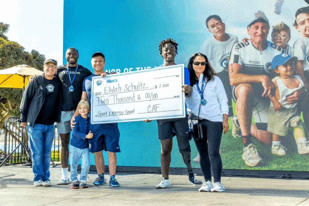 Youth athlete Elijah Shultz recieiving a sportss expense grant at the san diego triathlon challenge smiling on stage