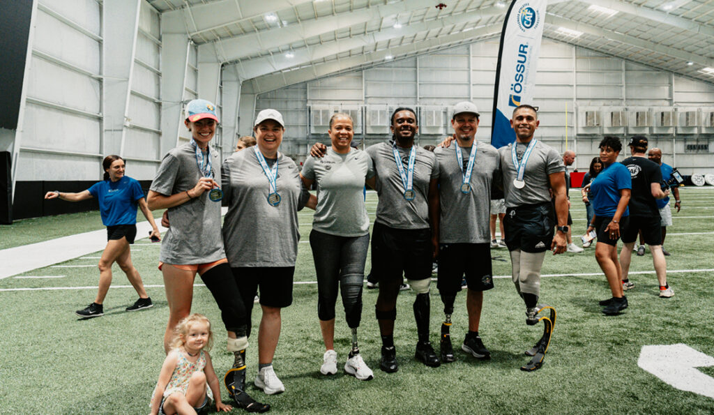 Group of participants with lower limb sports prostheses pose for a photo at an Ossur clinic