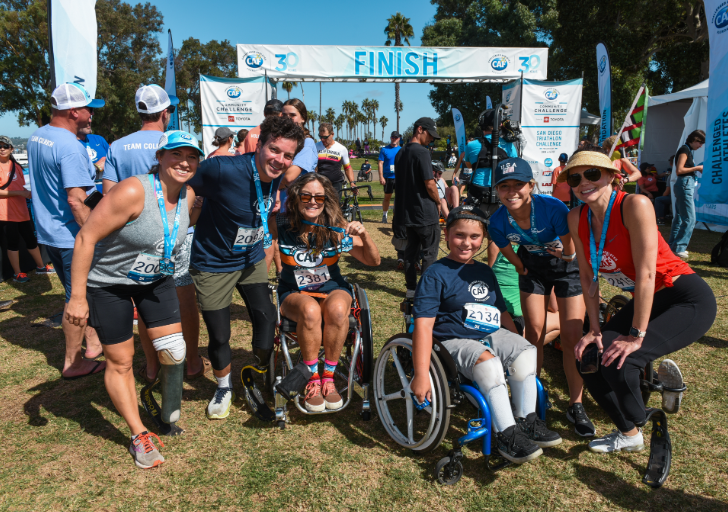 Participants with and without physical disabilities gather at the finish line during the Challenged Athletes Foundation San Diego Triathlon Challenge, celebrating the completion of the event.