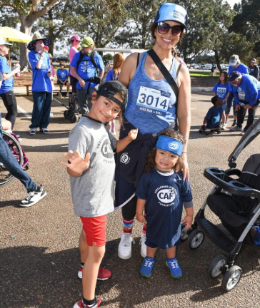Two young children and their parent, all wearing CAF shirts, pose together at the 5K Walk + Roll.