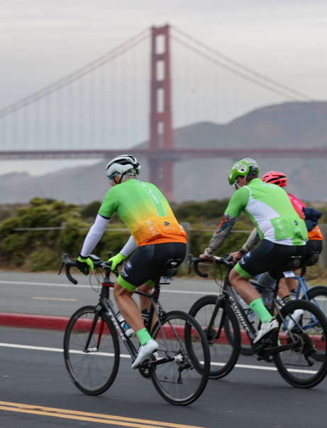 Cyclists in green and orange jerseys ride toward the Golden Gate Bridge during the Million Dollar Challenge