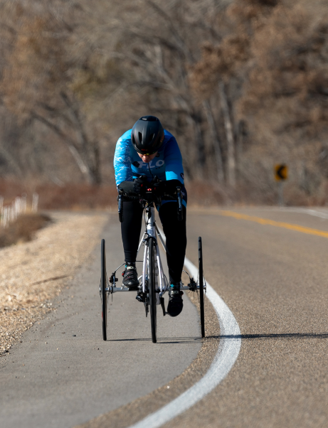 Athlete rides a handcycle on a road, demonstrating endurance and determination during a virtual challenge.