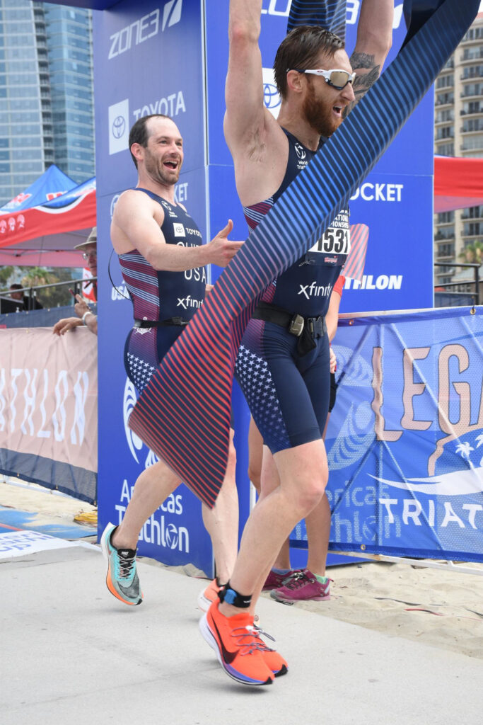Brad Snyder breaking the tape with guide Greg Billington celebrating behind him at the USA Paratriathlon National Championships