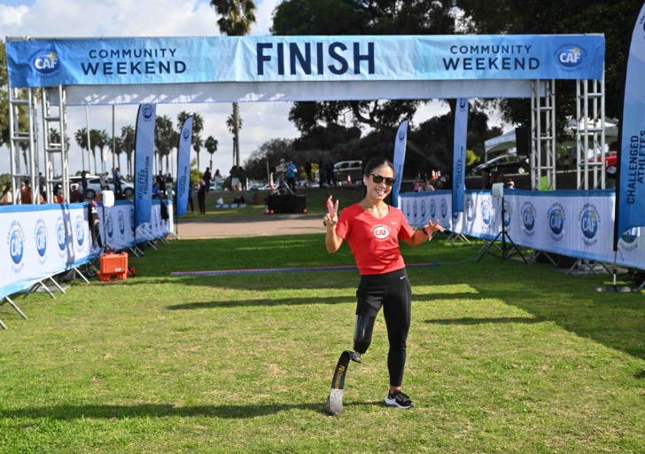 Scout Bassett smiling and posing under the finish line banner at CAF Community Weekend