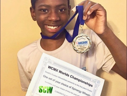 Young athlete proudly holds a medal and certificate after winning first place at the WCMX World Championships