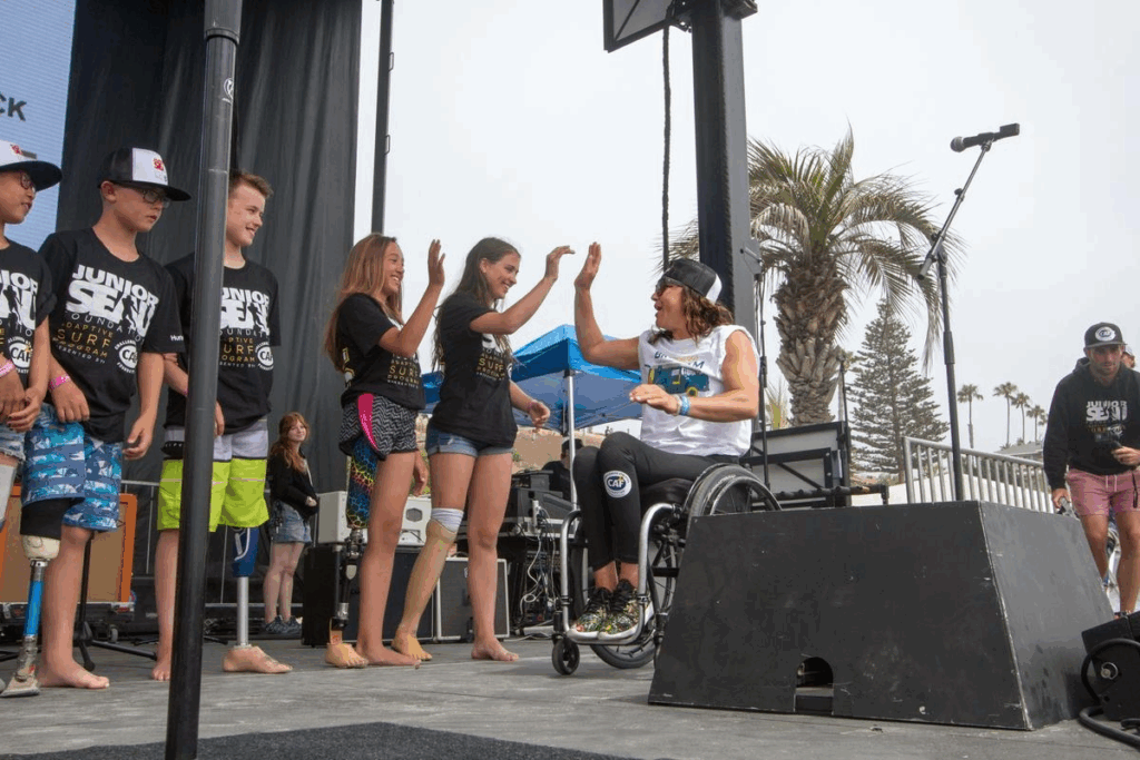 Alana Nichols in a wheelchair high-fiving young athletes on stage at Bro-Am in San Diego