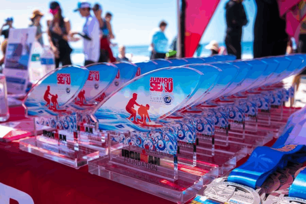 Row of colorful Junior Seau Foundation Adaptive Surf Program trophies displayed on a table at the beach