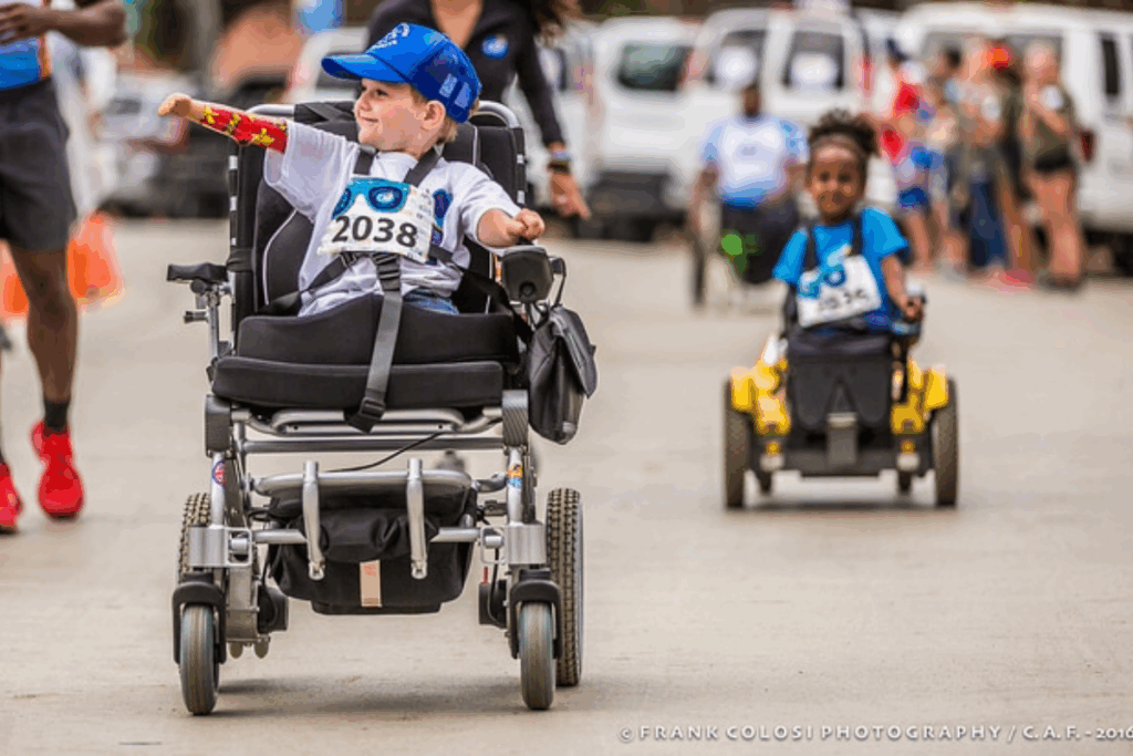 Young athlete using a power wheelchair races with determination during a CAF SDTC Kids Run.