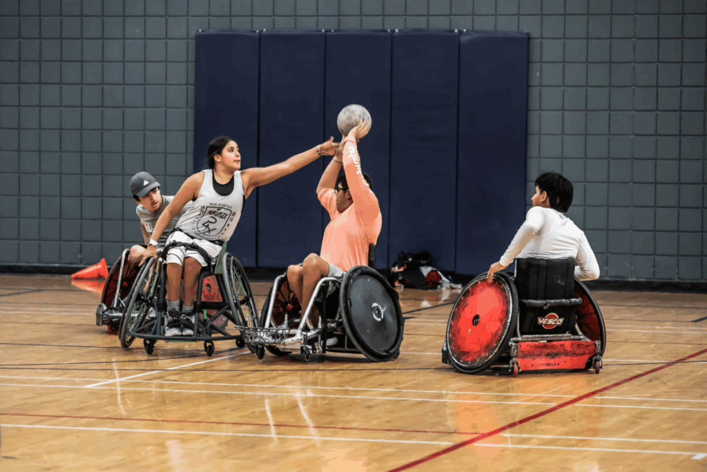 Wheelchair rugby athletes compete in a scrimmage, with one player blocking a pass attempt