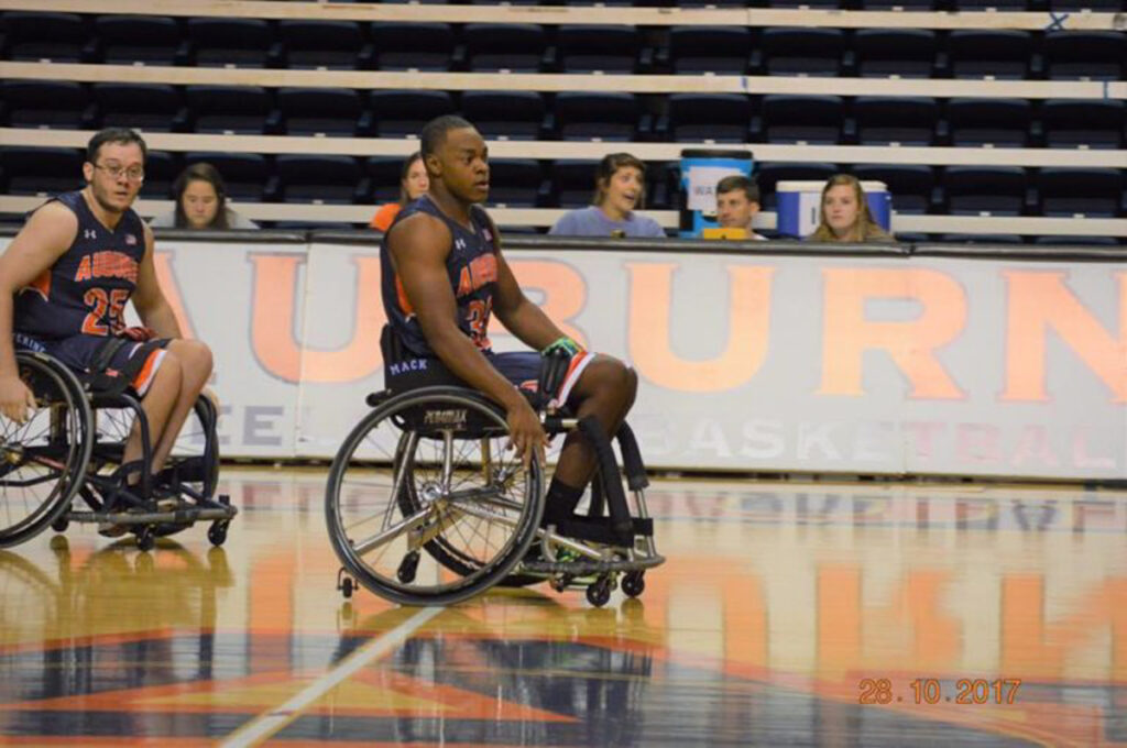 Two Auburn wheelchair basketball players on the court during a game, with "AUBURN" visible in the background.