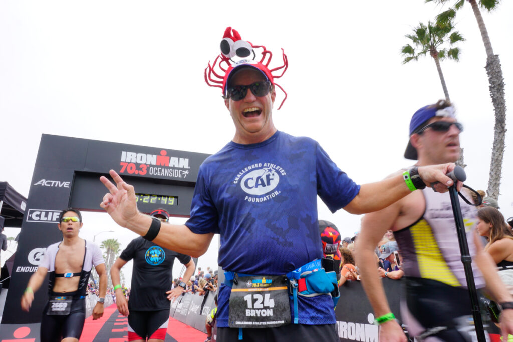 Participants at the Ironman 70.3 Oceanside event, including a smiling man with a lobster hat.