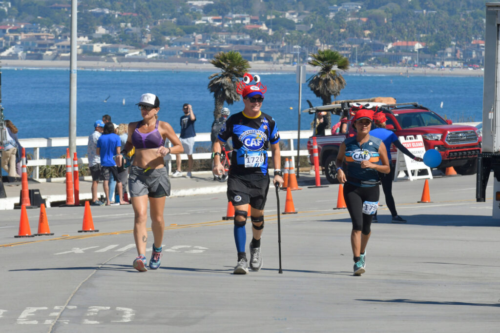 Runners participating in a racetrack along a seaside road with spectators in the background and the ocean view.