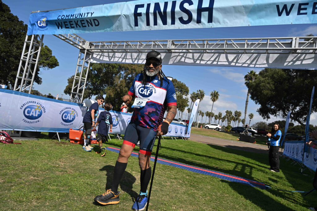 An athlete with a prosthetic leg crossing a finish line at an event by the Challenged Athletes Foundation.