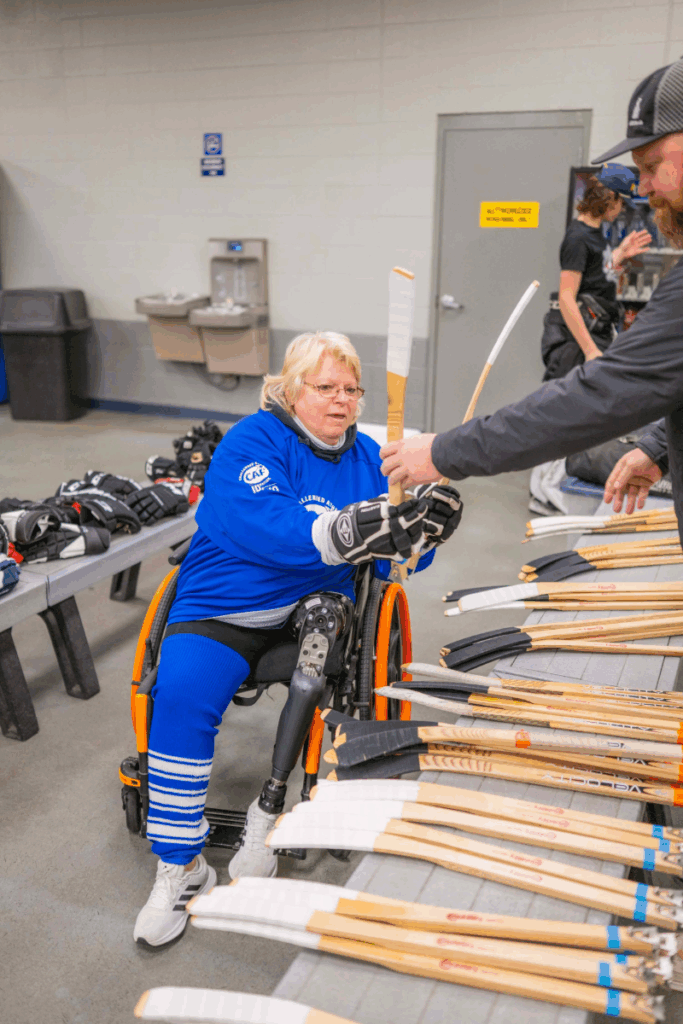 Sled hockey player picking out sticks 