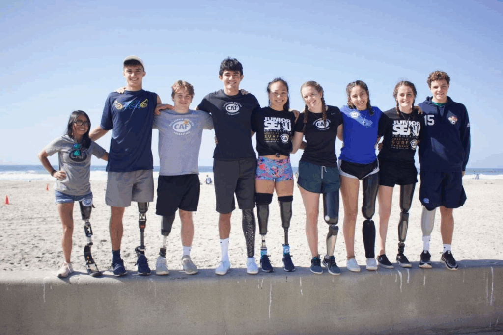 Group of five young women with limb differences smile together at the finish line of the San Diego Triathlon Challenge 5K event.